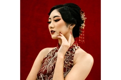 Chinese woman wearing traditional outfit with left hand touching cheek while looking to the left