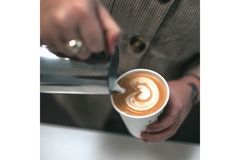 A man pouring coffee into a to-go coffee cup.