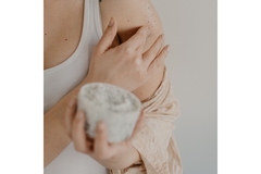 A woman putting cream on her shoulder.