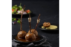 Image Three meatballs on a plate on top of a table.