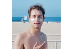 Man with sunscreen on cheeks with beach in background