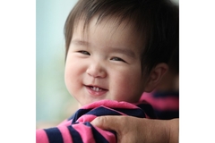 Image A cute baby smiles and looks toward us.