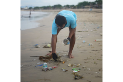 A man picking up plastic from off the beach.