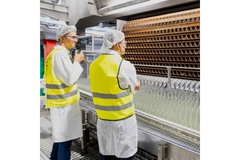 Men standing in front of glass bottling line.