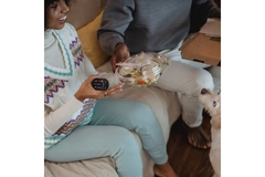 Family sitting on couch eating salad from single-use plastic bowl.