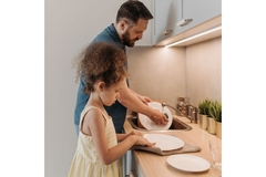 Image father washing dishes next to daughter handing over plates.