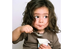 A little girl eating yogurt.