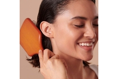 Image A woman with short hair brushing her hair while smiling.