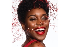 Image woman wearing makeup laughts with mouth open, bearing teeth.