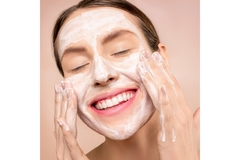Image A woman washing her face while smiling.