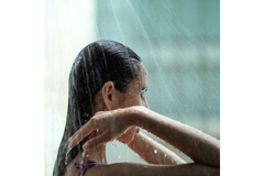 Image Woman's head with long hair facing right under a shower.