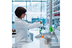 Image Woman facing right in a lab holding a beaker.