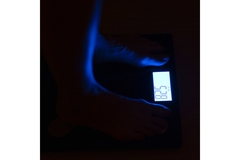 Image A person stands on a scale in the dark.