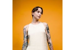 Image Woman with short hair and plain sleeveless shirt with tattoos on arms revealed.