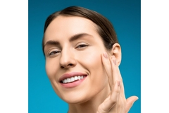 Image close up shot of womans face who gently touches her right cheek.