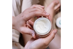 Image hands holding a small open container of moisturizer