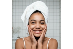 Image Smiling girl hold her checks with her hands flat, wearing a wrapped towel on her head