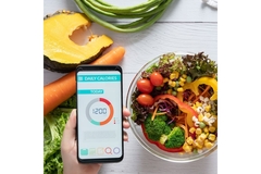 Bowl with salad and someone checking calorie count on their phone.