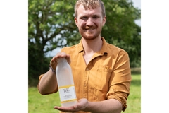 A man holding a refillable milk bottle made from plastic.