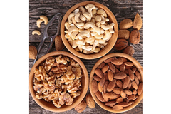 Image Three bowls of nuts are placed on a wood table.