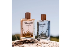 Image Two rectangular perfumes bottles with cylindrical lids on top of a rock