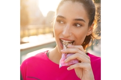 Image Sporty woman eating a fruit and nut bar.