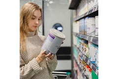 Image Woman looking at an infant milk formula tub in a store.