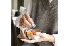 Image Woman taking a gummy from a metal container.