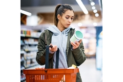 Image Young woman checks product label in supermarket.
