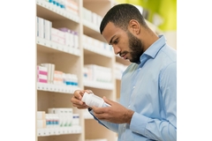 Image Man looking at supplement bottle in store.