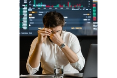 Image Man behind a computer who is pinching his eyes.