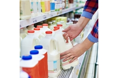 Image A hand reaching for a milk carton in a supermarket.