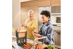 Image People standing in kitchen with food and compostable bin bag.