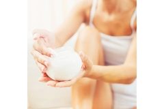 Image A woman applying lotion on her legs.