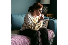 Image A woman coughing on a couch.