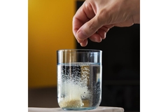 Woman throws effervescent tablet in water.