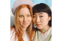 Two young women wearing bright colorful makeup.