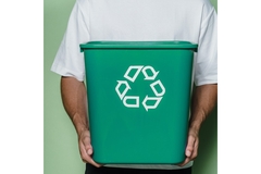 Image A man holding a green recycling bin.