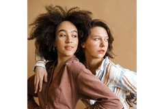 Image Two girls, one with curly afro and another with wavy hair with hands on hip pose looking to right.