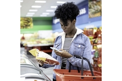Image Woman is shopping in supermarket and scanning barcode with smartphone.