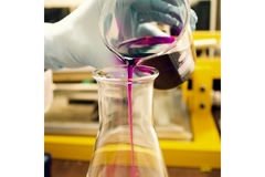 Image hand wearing gloves pours liquid into beaker in lab