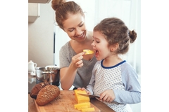 Image A mother feeding her daughter with a spoon.