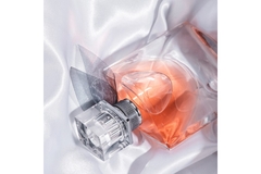 Image A bottle of perfume on the bed.
