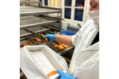 Image A woman in a factory holding a corrugated cardboard box.