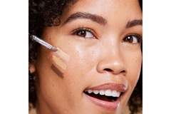 A woman applying foundation to her face.