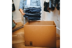 Image person putting denims into a cardboard box