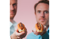 Image Two people are holding hotdogs.