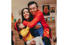 Image A family with the man hugging a woman who is holding a young child and they all look extremely happy.