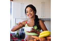 Image Fit woman in sports outfit holding spoonful of fruit to her face.