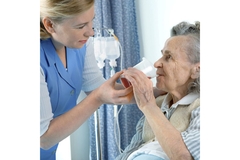 Doctor feeding a senior woman lying in a hospital bed.